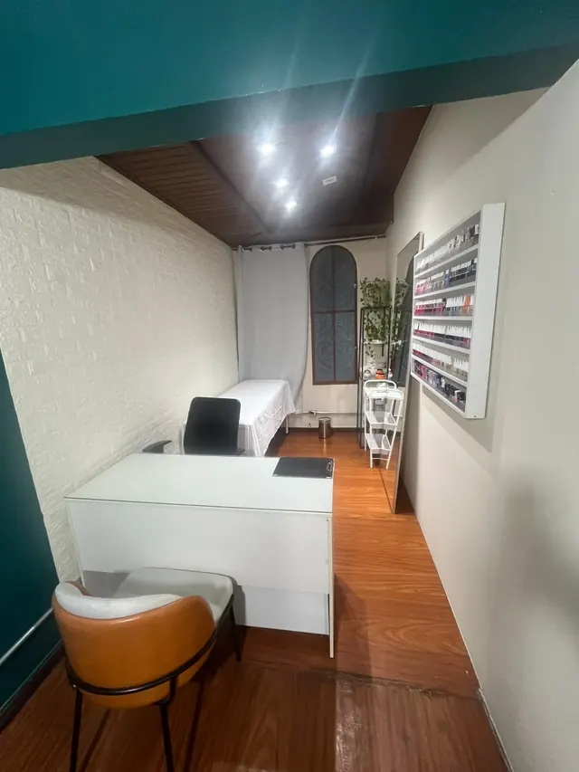 Sala de atendimento do Espaço Maura Cunha, com poltrona, parede de esmaltes e janela decorada